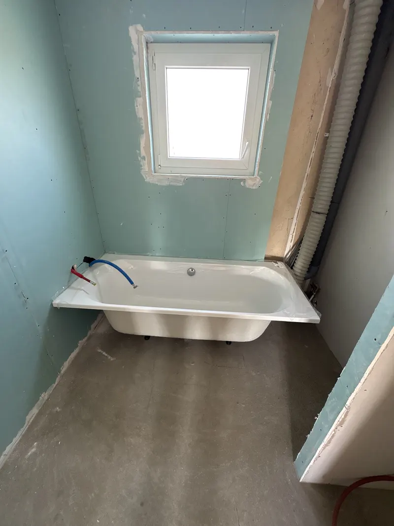 Baignoire posée dans une salle de bain en rénovation, avant la finition des murs